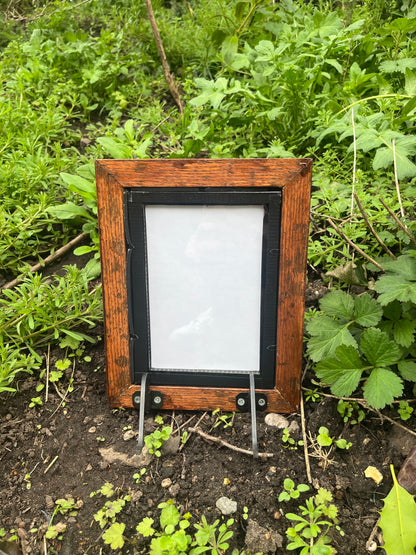 Wooden frame with a glass cover on a green leafy background